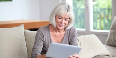 Senior woman smiles while using tablet computer at home