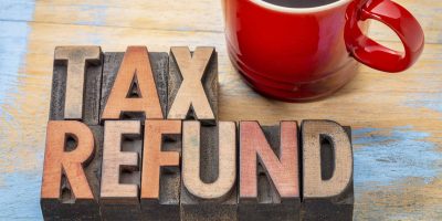 The words tax refund sit next to a cup of coffee