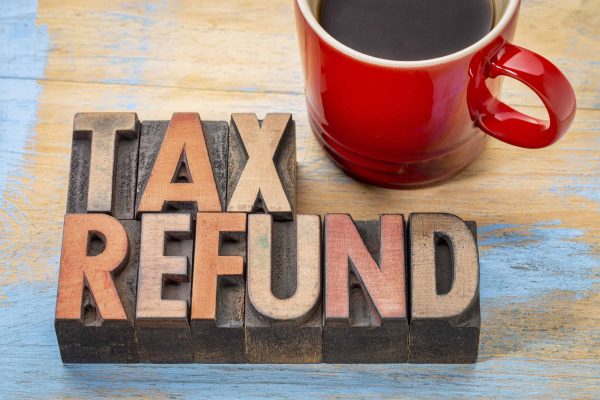 The words tax refund sit next to a cup of coffee
